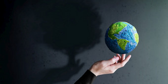 世界地球一天环境、社会和治理概念绿色能源可再生和可持续发展的资源环境和生态哪手手势悬浮绿色<strong>手工制作</strong>的全球大树影子阴影的墙
