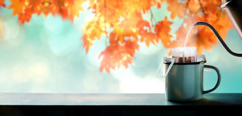 享受咖啡秋天和秋天季节使热咖啡倒水从水壶成即时咖啡滴袋模糊枫木叶树背景