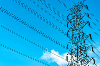 高电压电塔和传输行电塔与蓝色的天空和白色云权力和能源保护高电压网格塔与线电缆分布站