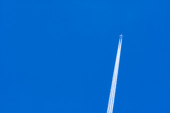 飞机与白色冷凝跟踪飞机飞机<strong>蓝色的天空</strong>和白色云与蒸汽小道旅行飞机概念小径排气气体从飞机引擎飞机与白色条纹