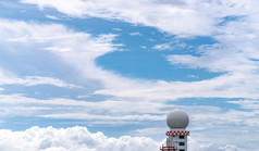 天气观察雷达圆顶站对蓝色的天空和白色毛茸茸的云航空气象观察站塔使用为安全飞机航空业务球形塔