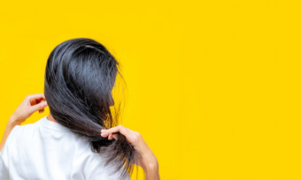 回来视图亚洲女人持有损坏的头发黄色的背景头发损失和薄头发问题女人干和脆黑色的长头发需要洗发水和护发素为水疗中心治疗