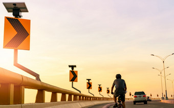 回来视图男人。穿头盔骑自行车的曲线路后面汽车安全开车和骑的路曲线路交通标志与太阳能面板能源户外锻炼健康的生活方式
