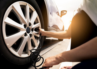 女人膨胀的轮胎女人检查轮胎压力和泵空气成的轮胎车轮车维护服务为安全之前旅行轮胎膨胀点填充空气的轮胎车