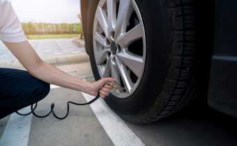 女人膨胀的轮胎女人检查轮胎压力和泵空气成的轮胎车轮车维护服务为安全之前旅行轮胎膨胀点填充空气的轮胎车