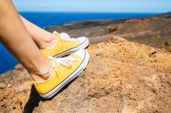 女人放松享受景观旅行者坐着岩石穿黄色的运动鞋夏天假期关闭高质量照片女人放松享受景观旅行者坐着岩石穿黄色的运动鞋夏天假期关闭