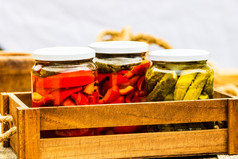 木箱与玻璃罐子与腌红色的贝尔辣椒和腌黄瓜泡菜孤立的罐子与各种腌蔬菜保存食物概念乡村作文