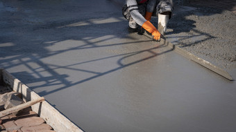 裁剪图像亚洲建设工人使用长三角形泥刀抹水泥的地板上建设网站