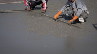 部分建设工人使用长三角形泥刀传播和抹水泥的地板上建设网站