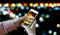 焦点女手粉红色的针织毛衣使用智能手机采取照片晚上光城市景观生活方式和技术概念