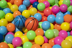 小橙色和蓝色的篮球玩具与色彩斑斓的塑料球球池