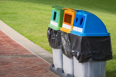 的角度来看一边视图色彩斑斓的回收垃圾垃圾箱为单独的浪费排序石头瓷砖人行道上与绿色草坪上公共公园区域