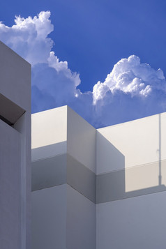 阳光和影子表面白色建筑墙对白色积雨云云蓝色的天空垂直框架
