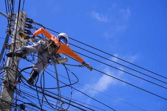 低角视图电工与安全设备和各种各样的工作工具安装电缆行和电系统电权力波兰对蓝色的天空背景