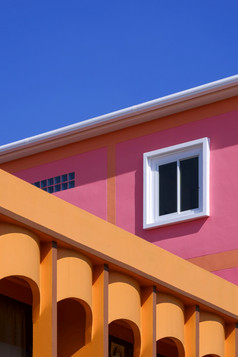 操纵技术为色彩斑斓的建筑背景设计柱廊橙色房子与粉红色的建筑对蓝色的清晰的天空的角度来看一边视图和垂直框架