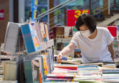 亚洲女人穿保护脸面具选择书书店购物购物中心