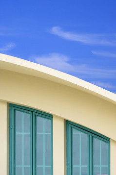 绿色玻璃阁楼窗户弯曲的屋顶现代黄色的建筑对白色云和蓝色的天空背景垂直框架