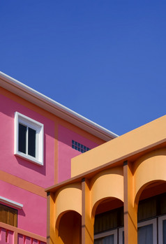 操纵技术为建筑背景设计色彩斑斓的柱廊橙色房子与粉红色的建筑对蓝色的清晰的天空的角度来看一边视图和垂直框架