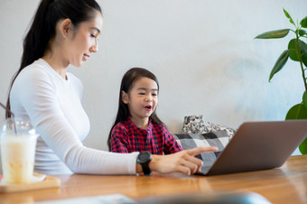 亚洲母亲是教学他们的女儿读书和使用<strong>笔记本电脑</strong>和技术为在线学习在学校假期<strong>首页</strong>教育概念和活动的家庭