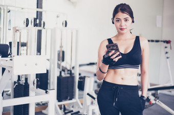 亚洲运动员运动服装时尚服装女运动员听音乐使用电话应用程序为健身<strong>活动</strong>跟踪器心率监控跟踪她的健康进步智能<strong>手机</strong>