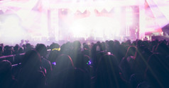 模糊的轮廓音乐会人群后视图节日人群提高他们的手明亮的阶段灯