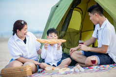 亚洲家庭微笑笑着说和享受野营和野餐的海滩与帐篷夏天假期