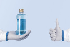 酒精防腐剂和消毒液瓶手和显示拇指医疗保健工人蓝色的颜色背景