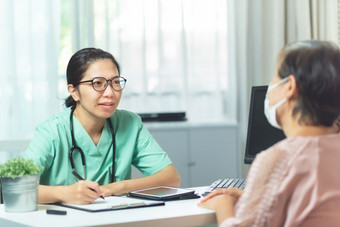 美丽的亚洲女人医生护士穿眼镜会说话的和给建议上了年纪的女人病人医疗房间的医院疾病生病了流感生病的人新冠病毒冠状病毒