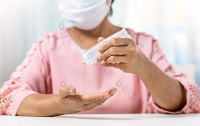 亚洲高级女人穿外科手术面具粉红色的衬衫倒手洗手液可移植的过来这里她的手掌和手为防止和保护冠状病毒新冠病毒流感大流行防腐剂卫生和健康的和健康哪