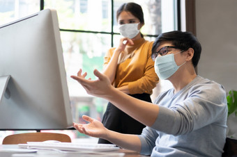 年轻的设计师保护脸面具为保护流感大流行病毒<strong>工作</strong>电脑监控在一起亚洲商人和女商人讨论和咨询业务<strong>工作会议</strong>办公室