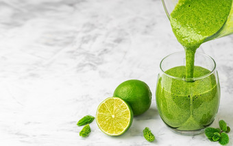 准备健康的排毒喝搅拌机奶昔新鲜的水果绿色菠菜和超级食物倒成玻璃健康的生活方式概念特写镜头