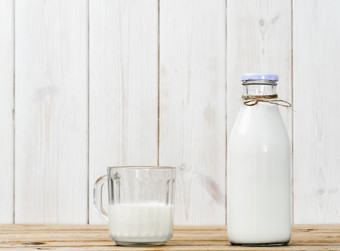 瓶牛奶和一半完整的玻璃与牛奶木古董表格白色木背景与复制空间新鲜的牛奶可重用的玻璃器皿健康的营养瓶牛奶和一半完整的玻璃与牛奶木表格