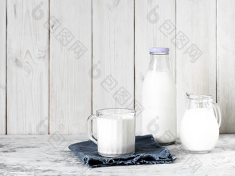 杯子与牛奶瓶牛奶和壶牛奶灰色的表格白色木背景与复制空间早餐概念健康的食物可重用的玻璃器皿杯子与牛奶瓶牛奶和壶牛奶灰色的表格