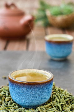 热绿色茶蓝色的茶碗石头表格蒸汽上升从的碗茶叶子下一个的杯特写镜头茶仪式最小的