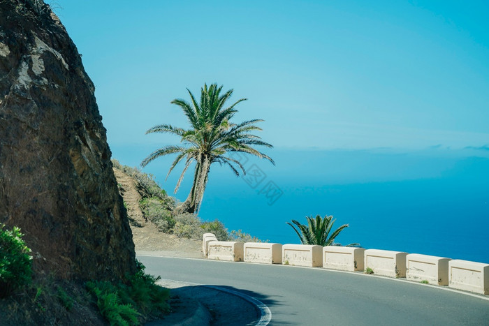 美丽的山路与棕榈树挂的边缘悬崖海洋背景路