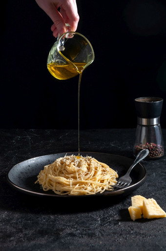 cacio佩佩意大利意大利面与奶酪和胡椒意大利面倒橄榄石油黑色的板黑暗背景cacio佩佩意大利意大利面与奶酪和胡椒意大利面倒橄榄石油黑色的板黑暗背景
