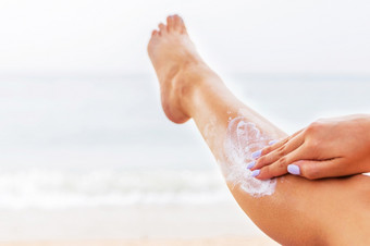 年轻的女人有休息的日光浴浴床的海滩和保护她的皮肤应用<strong>防晒</strong>霜她的腿年轻的女人有休息的日光浴浴床的海滩和保护她的皮肤应用<strong>防晒</strong>霜她的腿