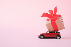 红色的玩具车交付礼物盒子与红色的丝带粉红色的背景的地方为文本销售生日圣诞节时间彼得堡俄罗斯7月