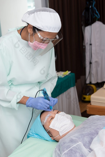 曼谷泰国五月身份不明的亚洲女人眉纹身专家眉纹身刺绣诊所使用新冠病毒预防政策保护使用面具和脸盾眉纹身诊所眉刺绣诊所