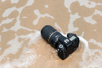 罗勇府泰国五月身份不明的摄影师演示防水数码单反相机相机与长焦镜头海滩湿从水海波当旅行和测试使用的极端的环境数码单反相机相机海滩湿从水海波