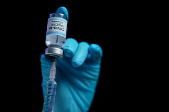 手蓝色的手套持有疫苗和注射器注射为预防免疫接种和治疗从电晕病毒感染