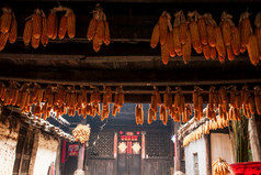 美丽的阳光照古老的中国人房子和玉米干燥挂周围的室内房子chengzi村的古老的村云南中国食物文化村旅游