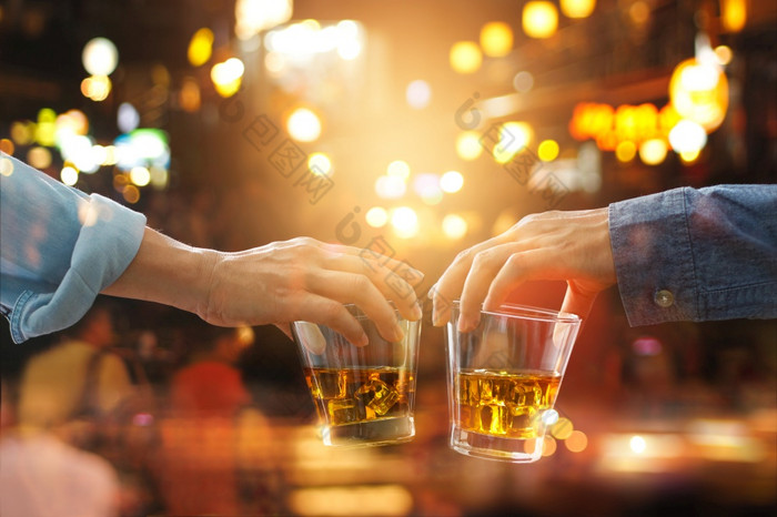 干杯无比的朋友与波本威士忌威士忌喝聚会，派对晚上后工作色彩斑斓的背景