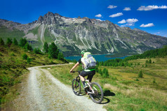 骑摩托车的人山污垢路美丽的景观的阿尔卑斯山脉