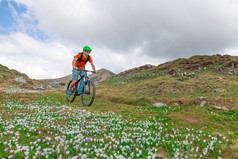 年轻的山骑摩托车的人游乐设施下来山草地春天在花