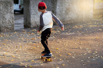 小城市男孩与一分钱滑板年轻的孩子骑的公园滑板城市风格城市孩子们孩子学习骑一分钱董事会