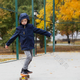 小城市男孩与一分钱滑板孩子滑冰秋天公园城市风格城市孩子们孩子学习骑一分钱董事会