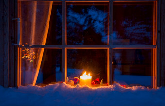 雪晚上窗口木房子的窗台上是圣诞节装饰和燃烧蜡烛雪木窗口圣诞节装饰和蜡烛