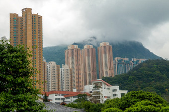 中国多云的一天在<strong>香港香港</strong>住宅摩天大楼对的背景树木繁茂的山和低云摩天大楼多山的在<strong>香港香港</strong>