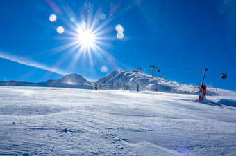 明亮的阳光明媚的天气的滑雪坡滑雪电梯和几个滑雪者白雪覆盖的滑雪坡和滑雪电梯和明亮的太阳